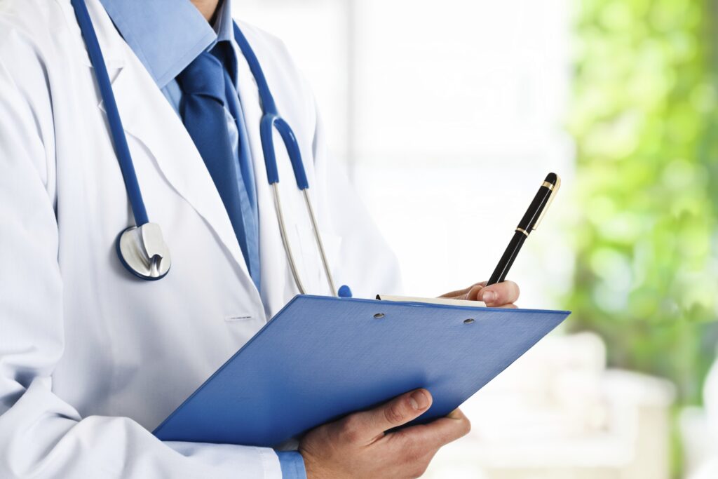 Médecin généraliste en consultation, prenant des notes sur l’état de santé d’un patient