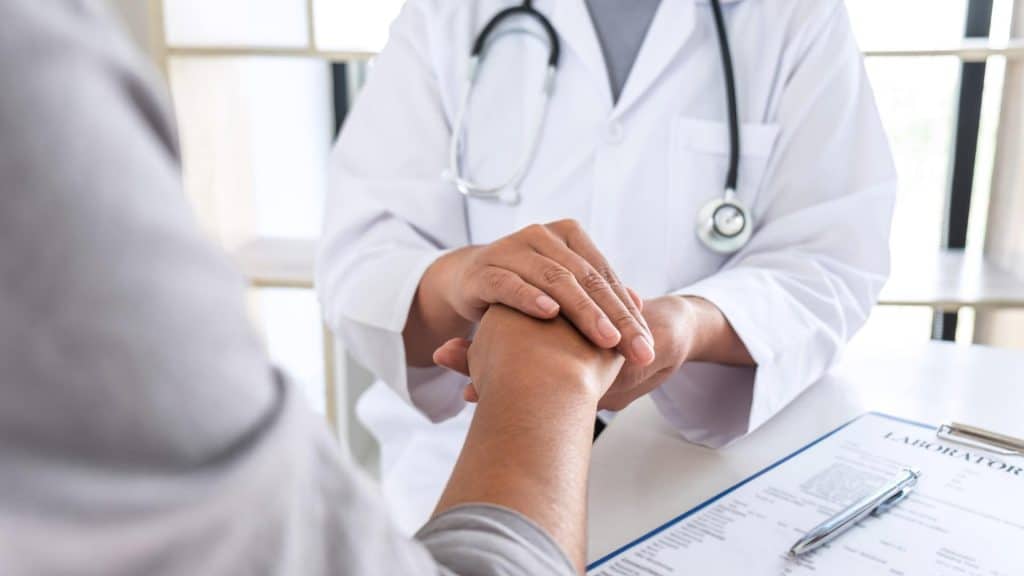 Médecin généraliste en consultation, prenant des notes sur l’état de santé d’un patient